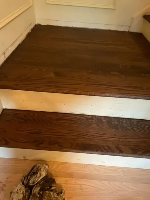 Dark stained stair treads with white risers during hardwood refinishing installation