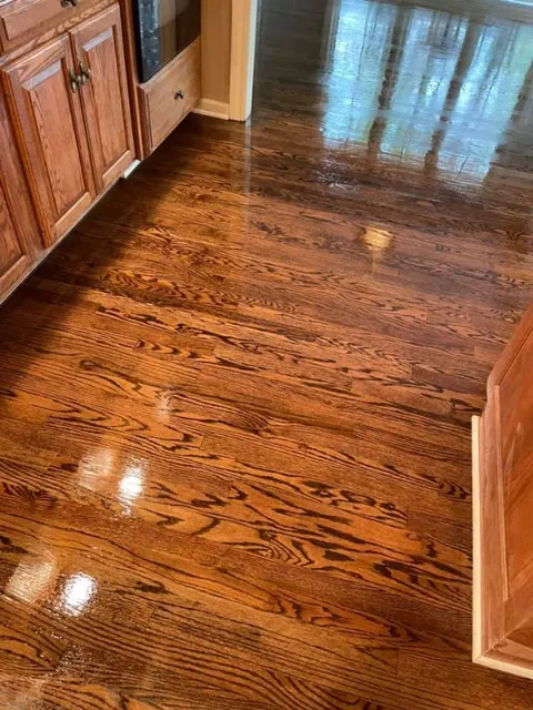 Glossy refinished hardwood floor beside wood cabinetry in a Rochester NY kitchen