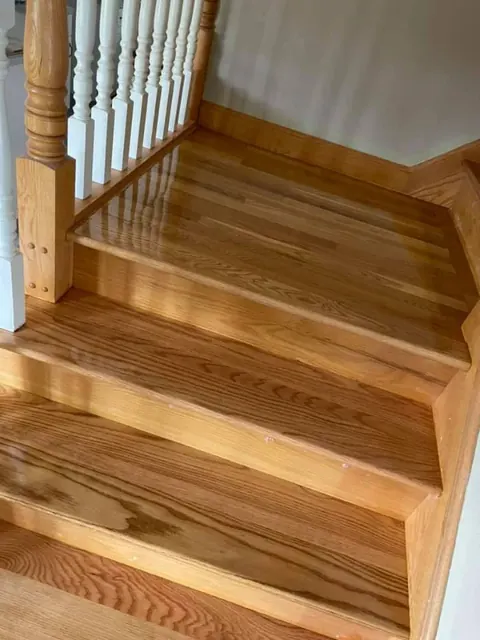Refinished wood staircase with polished treads and white balusters