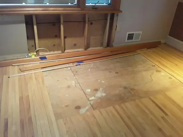 Half-completed hardwood floor installation showing new boards being laid