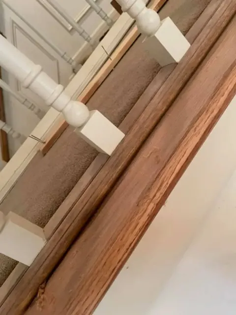 Hardwood floor installation under a staircase railing in a Rochester NY home