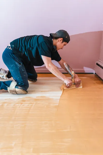 Refinished hardwood floors extending from a hallway into an adjacent room