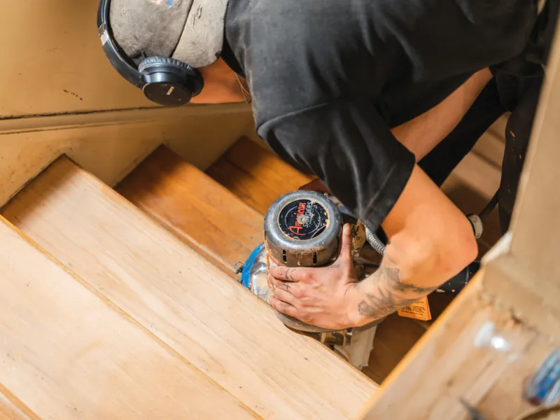 worker refinishing hardwood stairs